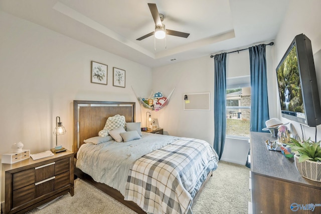 bedroom featuring ceiling fan, carpet flooring, visible vents, baseboards, and a tray ceiling