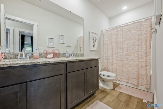 full bathroom featuring a sink, double vanity, wood finished floors, and toilet