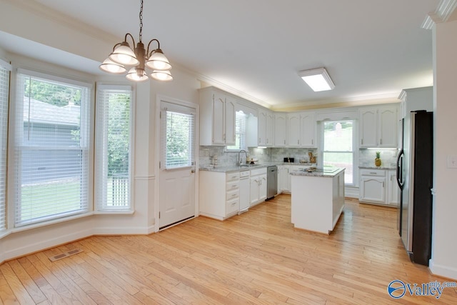 kitchen featuring freestanding refrigerator, a sink, dishwasher, crown molding, and a chandelier