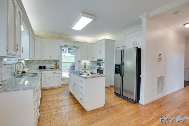 kitchen with stainless steel appliances, a sink, white cabinets, crown molding, and tasteful backsplash