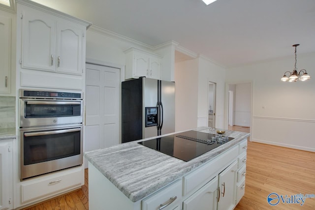 kitchen featuring appliances with stainless steel finishes, light wood-type flooring, white cabinets, a chandelier, and a center island