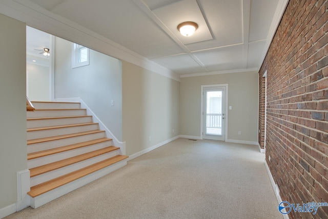 carpeted empty room with brick wall, stairs, baseboards, and ornamental molding