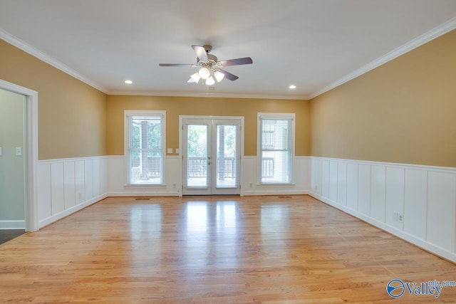 spare room featuring ceiling fan, light wood finished floors, a wainscoted wall, french doors, and a decorative wall