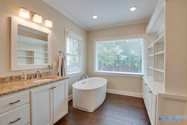 full bath with baseboards, crown molding, vanity, wood finished floors, and a freestanding tub