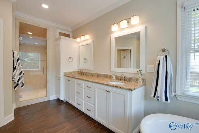 full bathroom with a shower stall, double vanity, ornamental molding, a freestanding tub, and wood finished floors