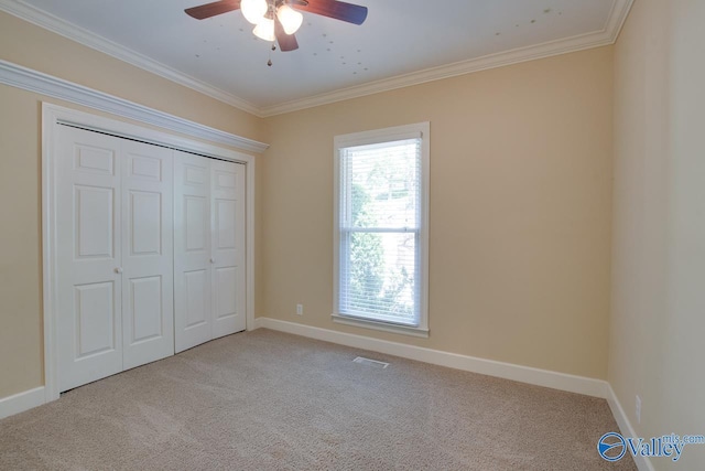 unfurnished bedroom with carpet, ornamental molding, baseboards, a closet, and a ceiling fan