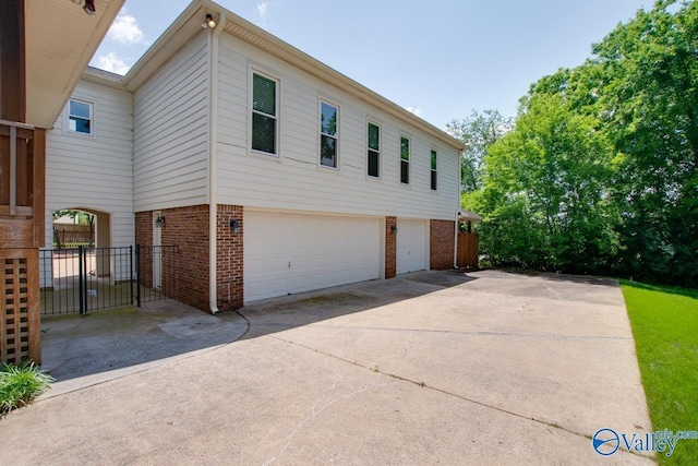 view of front of property with brick siding, a garage, concrete driveway, and fence