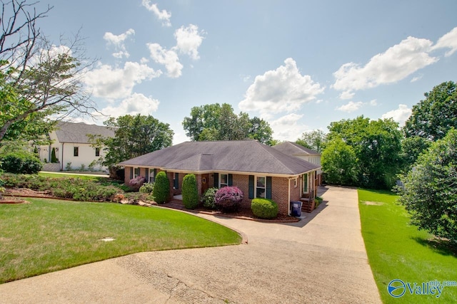 ranch-style home featuring concrete driveway, brick siding, and a front yard