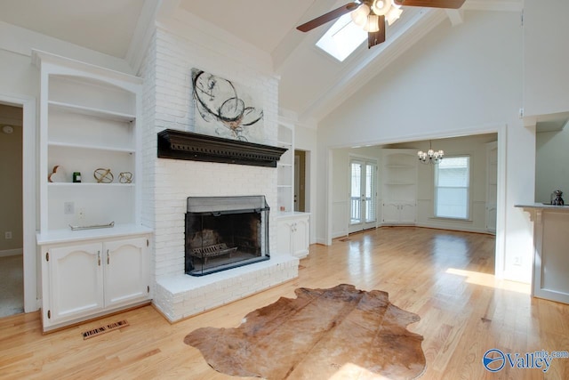 unfurnished living room with a fireplace, a chandelier, ceiling fan, high vaulted ceiling, and built in features