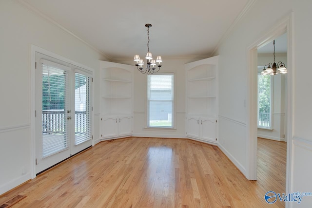unfurnished dining area with a chandelier, crown molding, light wood-style floors, and plenty of natural light