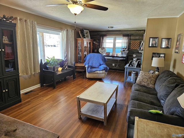 living room featuring ceiling fan, wood-type flooring, log walls, and a textured ceiling