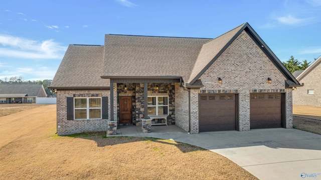 view of front of property with driveway, a garage, roof with shingles, a front lawn, and brick siding