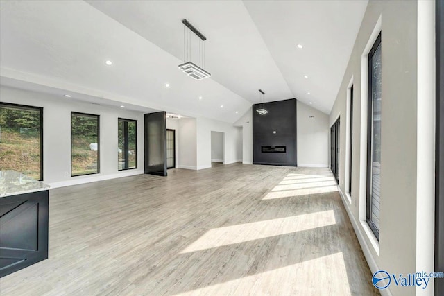 unfurnished living room featuring visible vents, vaulted ceiling, light wood-style floors, a fireplace, and recessed lighting