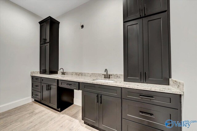 interior space with sink, light wood-type flooring, and light stone counters