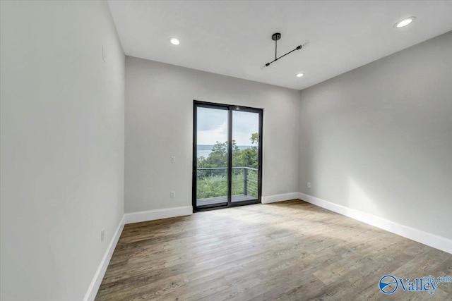 unfurnished room with recessed lighting, wood finished floors, and baseboards