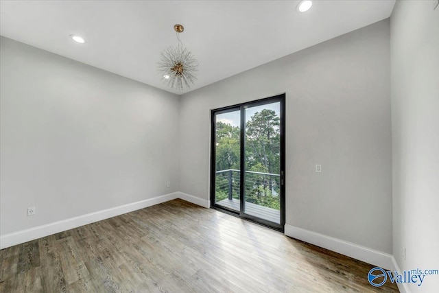 spare room with baseboards, wood finished floors, and recessed lighting