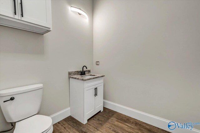 bathroom with toilet, hardwood / wood-style floors, and vanity