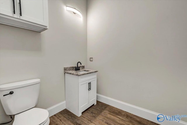 bathroom featuring baseboards, vanity, toilet, and wood finished floors