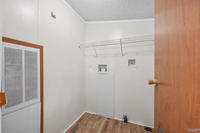 clothes washing area with hookup for a washing machine, light wood-type flooring, a textured ceiling, and crown molding