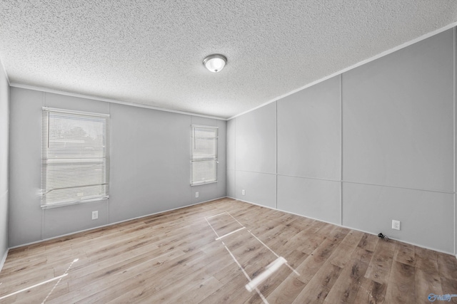 empty room with crown molding, light hardwood / wood-style flooring, and a textured ceiling