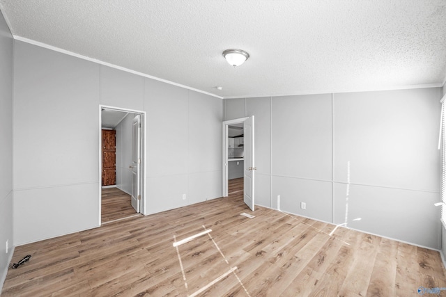 spare room with hardwood / wood-style floors, crown molding, and a textured ceiling