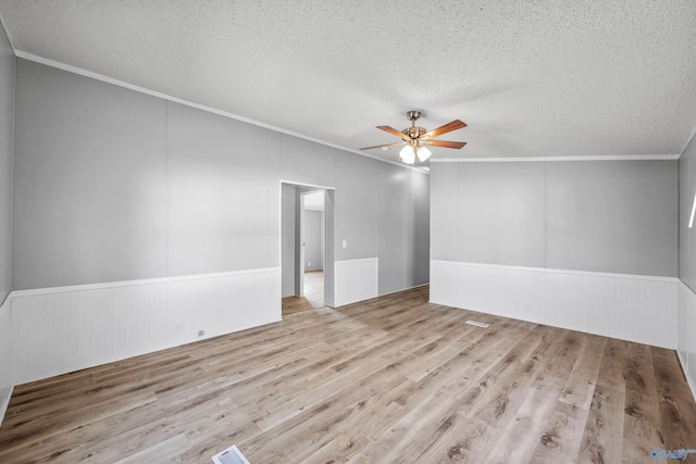 spare room featuring ceiling fan, crown molding, a textured ceiling, and light hardwood / wood-style flooring