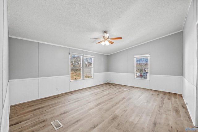 unfurnished room featuring ceiling fan, a healthy amount of sunlight, a textured ceiling, and light wood-type flooring