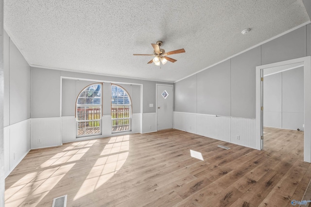 unfurnished room featuring ceiling fan, light hardwood / wood-style floors, ornamental molding, and a textured ceiling