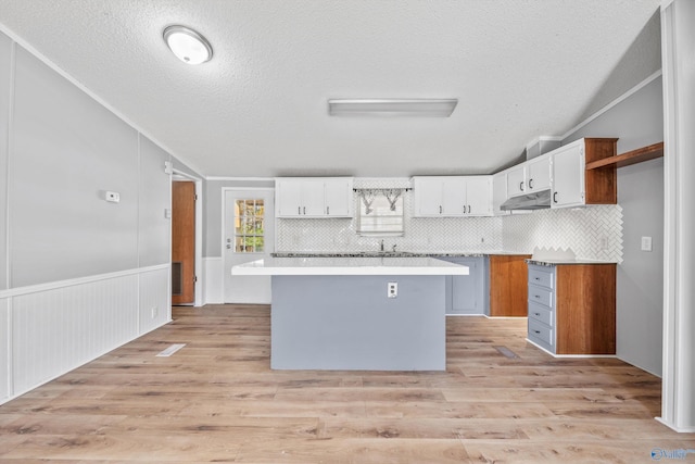 kitchen with light hardwood / wood-style flooring, white cabinetry, tasteful backsplash, and a kitchen island