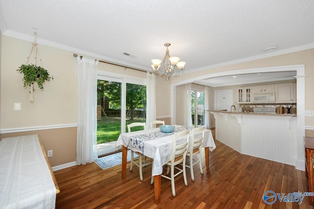 1867 Shellbrook Dr, Huntsville, AL 35806 - dining area with wood-type flooring, a chandelier, ornamental molding, baseboards, and arched walkways
