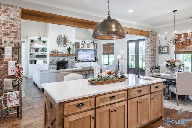 kitchen featuring sink, decorative light fixtures, a kitchen island, a brick fireplace, and dark hardwood / wood-style flooring