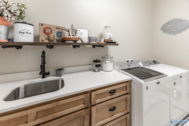 clothes washing area with separate washer and dryer, cabinets, and sink