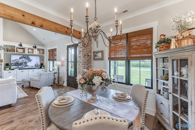 dining room featuring a notable chandelier, vaulted ceiling, a healthy amount of sunlight, and hardwood / wood-style floors