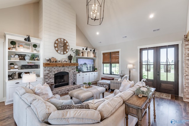 living room featuring an inviting chandelier, french doors, dark hardwood / wood-style floors, a brick fireplace, and high vaulted ceiling