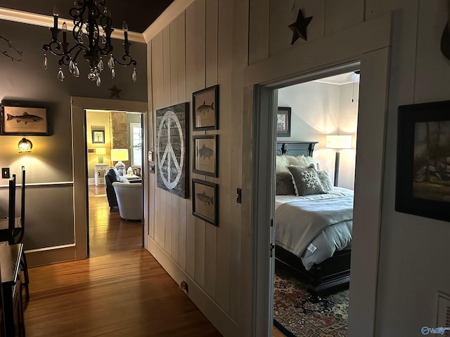 corridor with crown molding, a chandelier, and hardwood / wood-style flooring