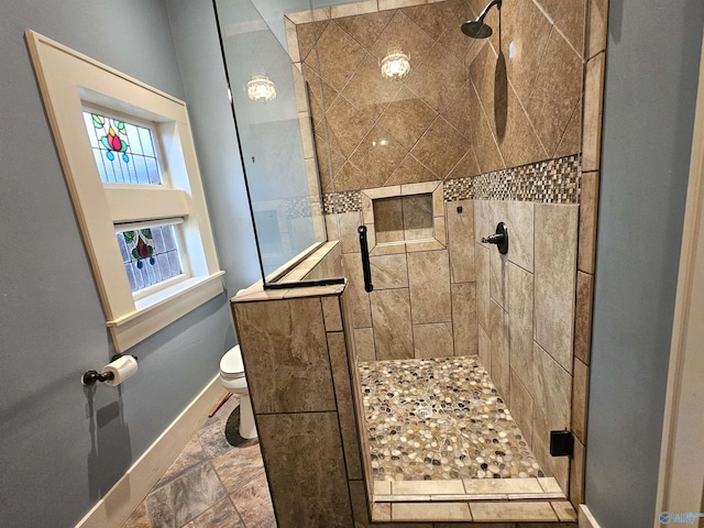 bathroom featuring tiled shower, tile patterned flooring, and toilet