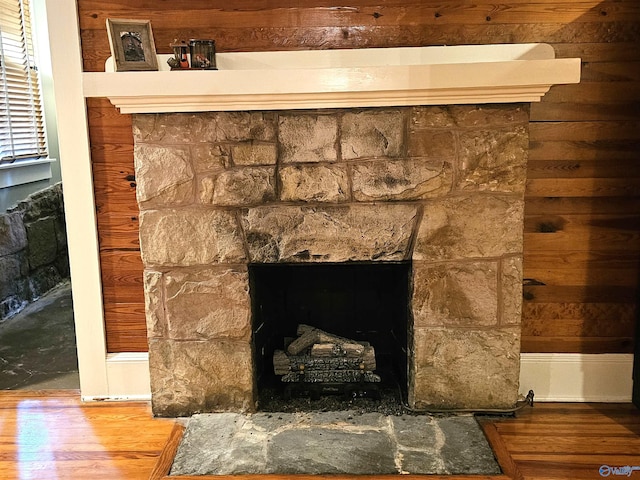 details with a stone fireplace and wood-type flooring