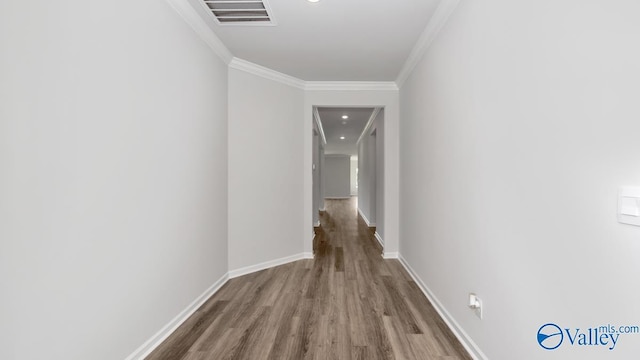 corridor featuring visible vents, baseboards, wood finished floors, and crown molding