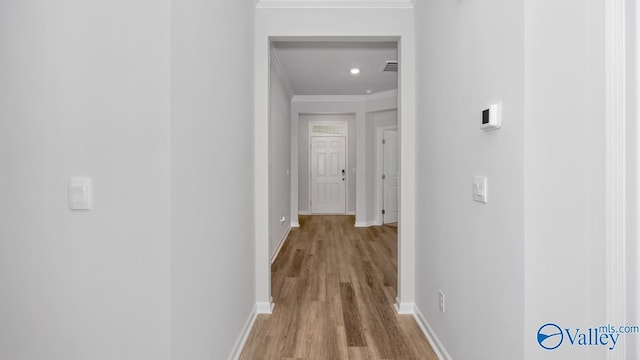 corridor featuring crown molding, baseboards, and wood finished floors