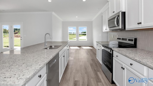 kitchen featuring backsplash, light wood-type flooring, ornamental molding, stainless steel appliances, and a sink