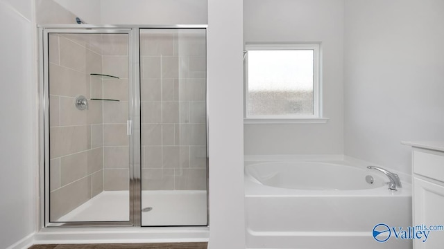 full bathroom with vanity, a garden tub, and a stall shower