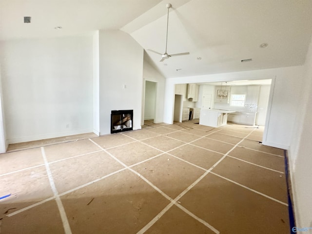 unfurnished living room featuring vaulted ceiling, ceiling fan, and a fireplace