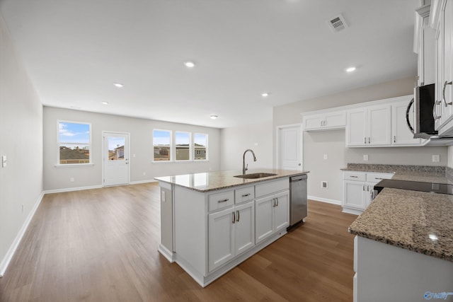 kitchen with appliances with stainless steel finishes, stone countertops, an island with sink, sink, and white cabinets