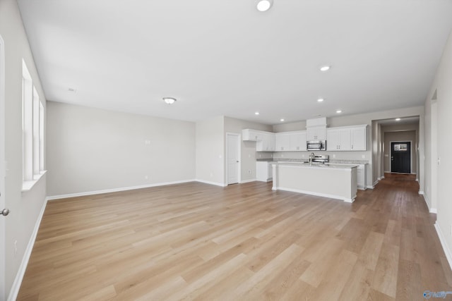 unfurnished living room with sink and light wood-type flooring