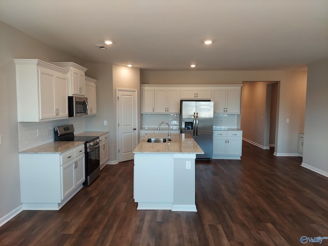 kitchen featuring appliances with stainless steel finishes, sink, white cabinets, a kitchen island with sink, and light stone countertops