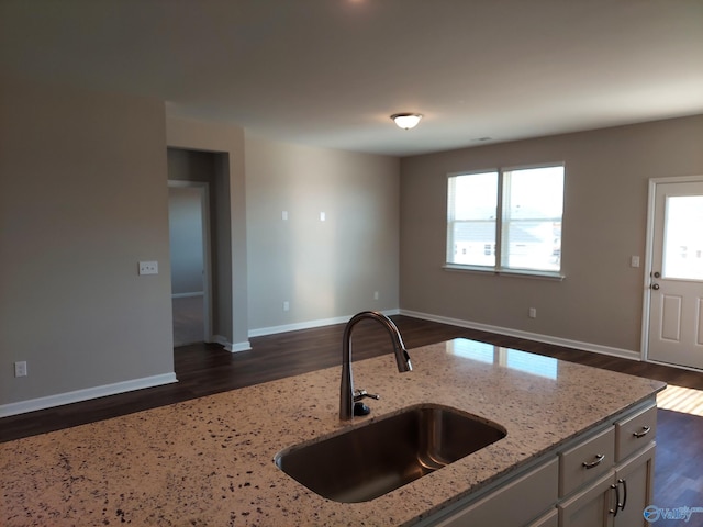 kitchen with plenty of natural light, sink, dark wood-type flooring, and light stone counters