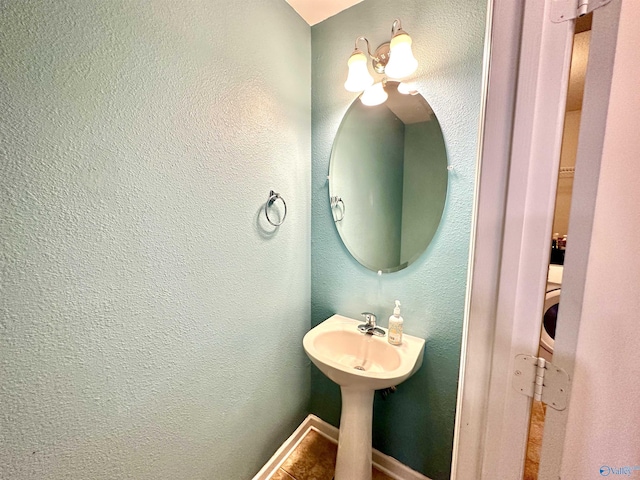 bathroom featuring a textured wall and baseboards