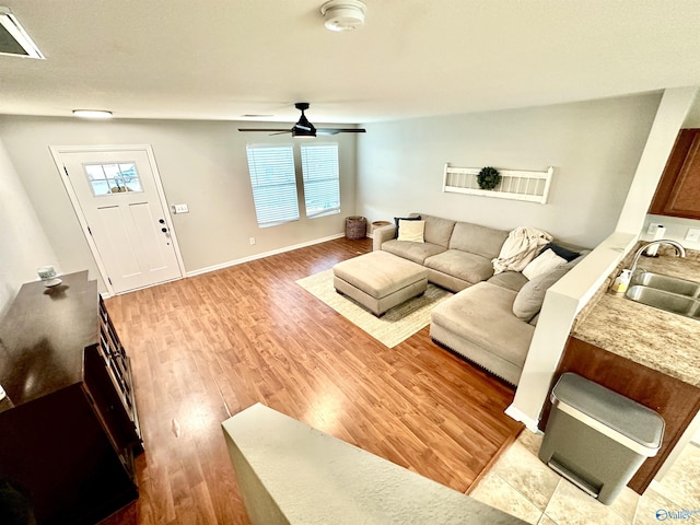 living room with light wood-style floors, baseboards, visible vents, and ceiling fan