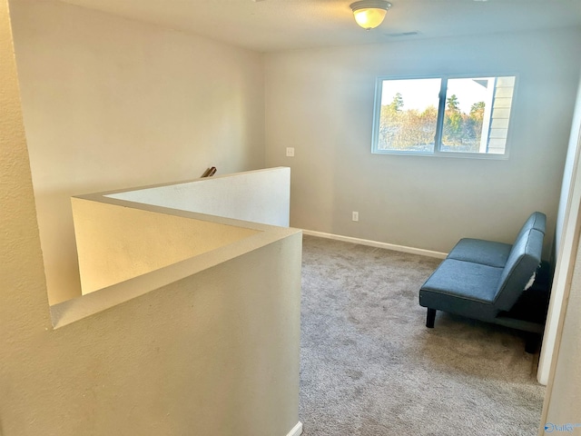 living area featuring carpet floors, an upstairs landing, and baseboards