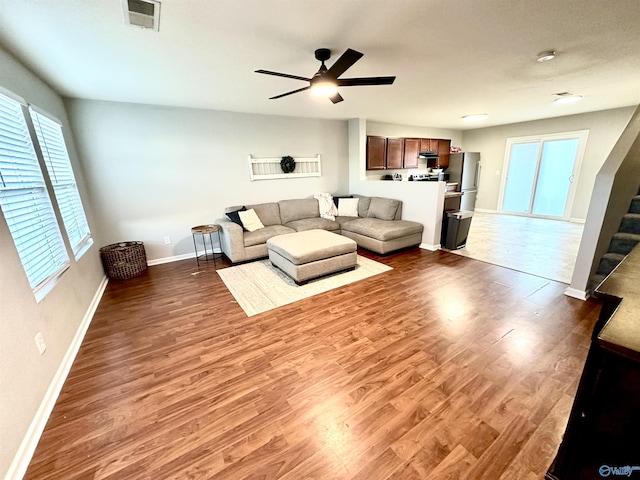 unfurnished living room featuring baseboards, visible vents, ceiling fan, wood finished floors, and stairs